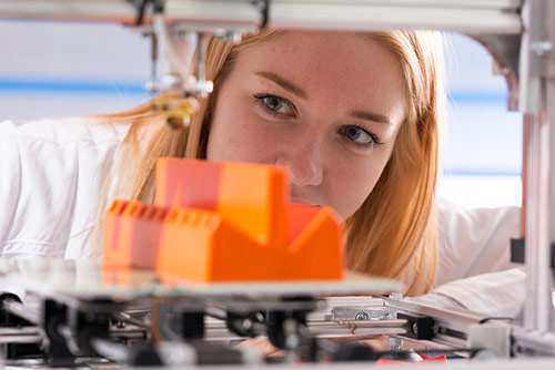 A woman monitoring a 3D printer